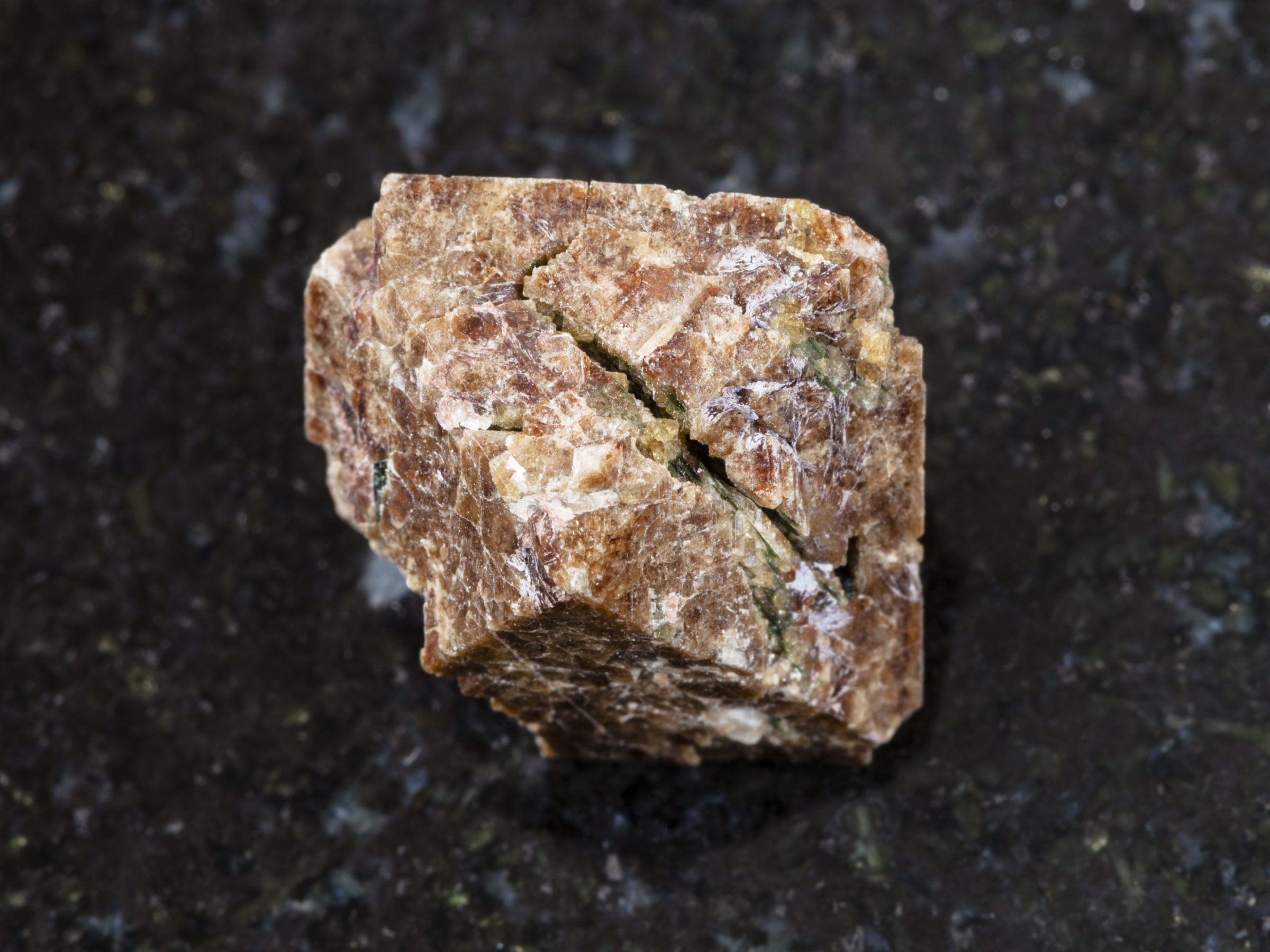 macro shooting of natural mineral rock specimen - crystal of Zircon gemstone on dark granite background from Marchenko Peak, Khibiny Mountains, Kola Peninsula, Russia